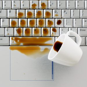 Coffee spilled on keyboard, close up shot. Damaged computer that needs reparation. Data safety and laptop insurance concept.